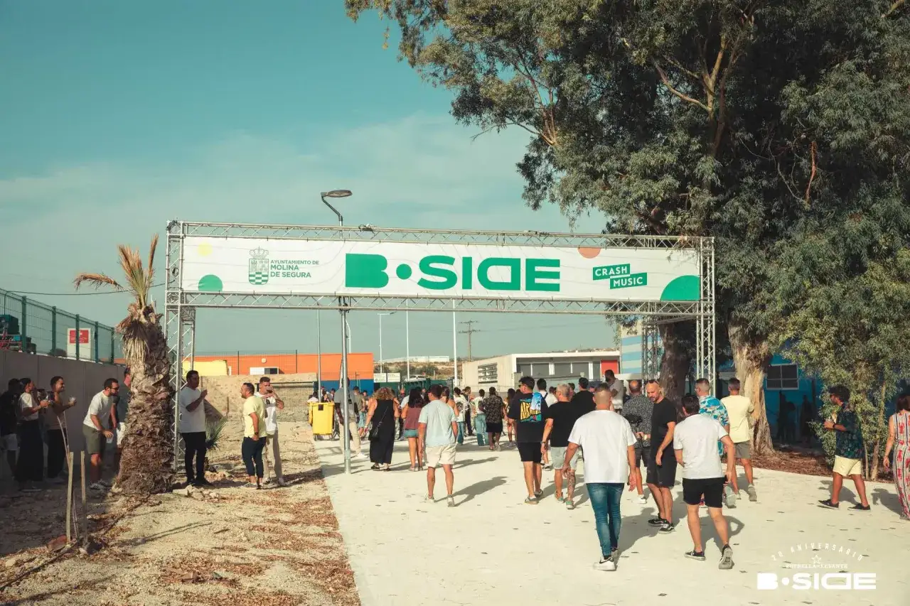 Gente camina bajo un arco de entrada con el logo de B-Side Murcia y Crash Music.