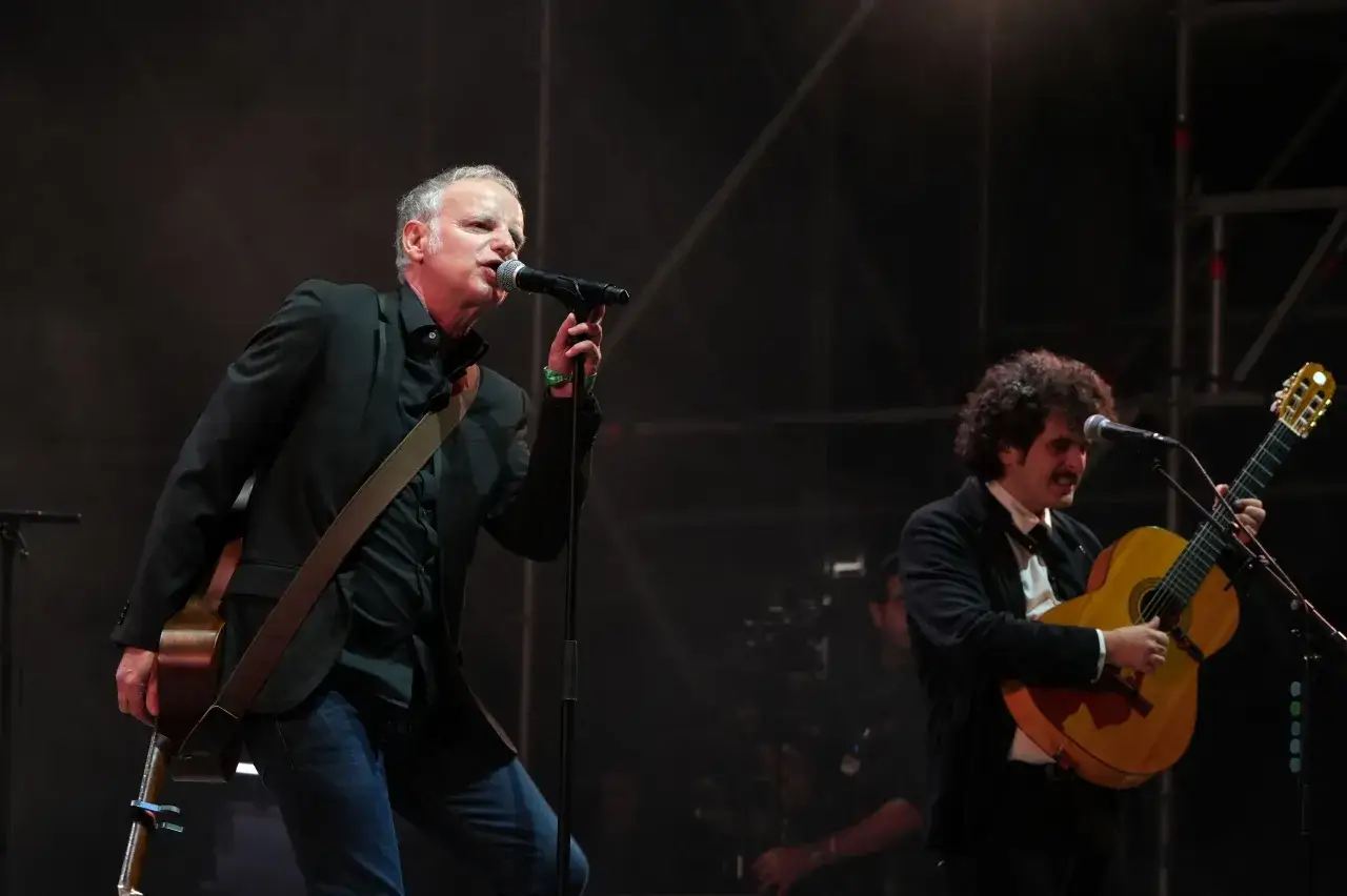 Dos miembros de Els Pets cantan y tocan la guitarra en un concierto.