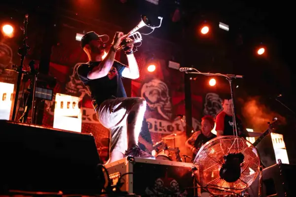 Músico con trompeta en un concierto de soria rock, con luces rojas y fondo de calaveras.